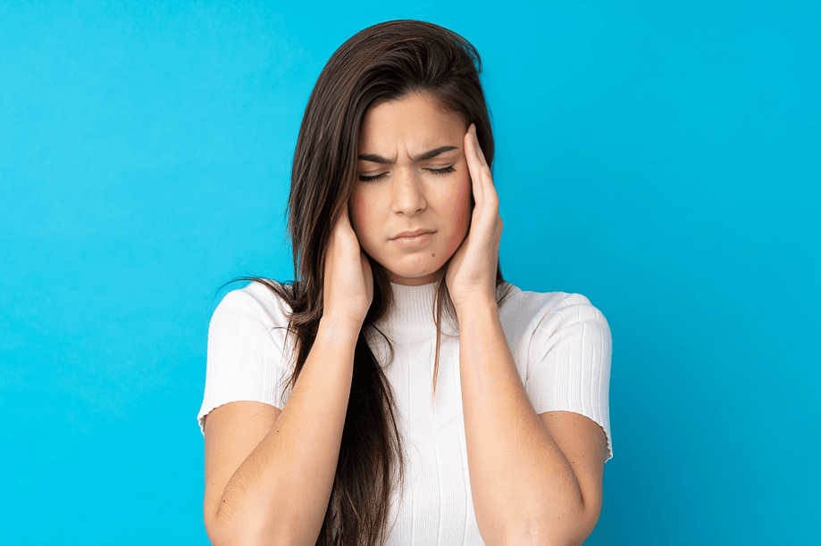 Young woman with headache, hands on temples.