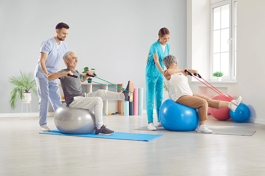 Therapists assist seniors with exercise using stability balls.