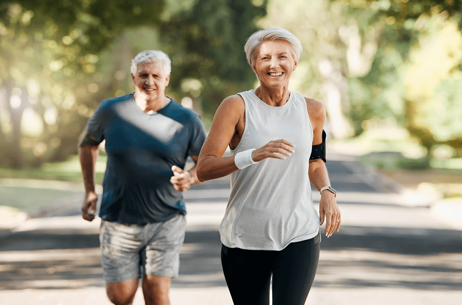 Two older adults happily jogging outdoors.