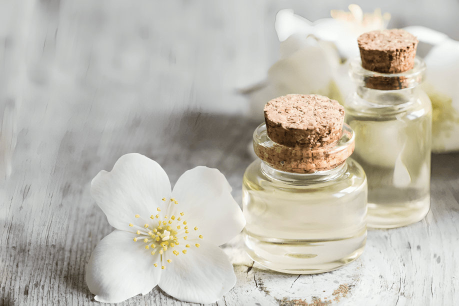 Two small bottles of essential oil with a white flower.