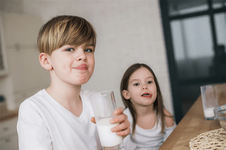 Two children with milk mustaches holding glasses.