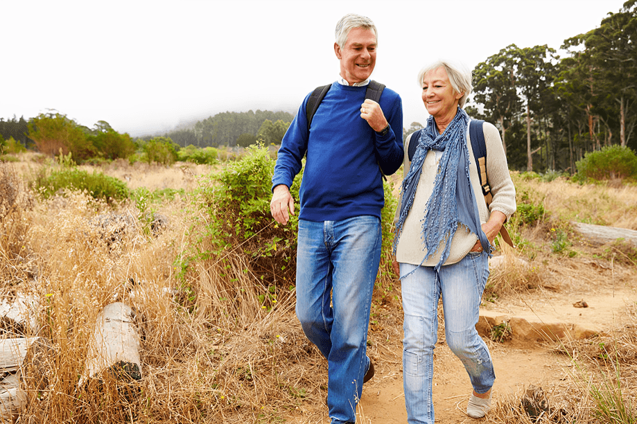  Smiling senior couple hiking on a nature trail.