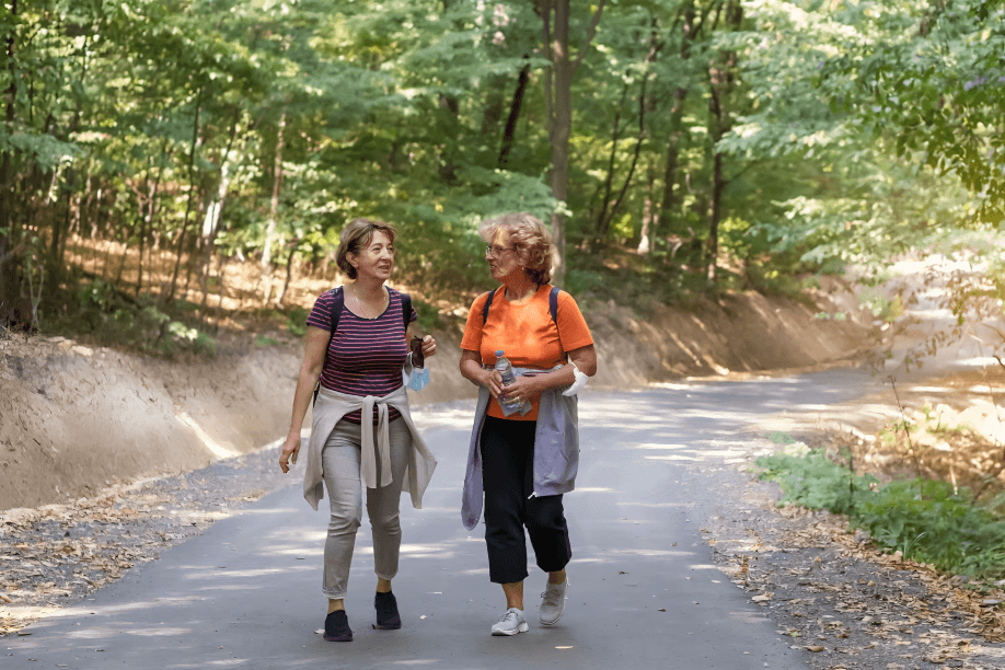 Two women walking and talking on a forest path.