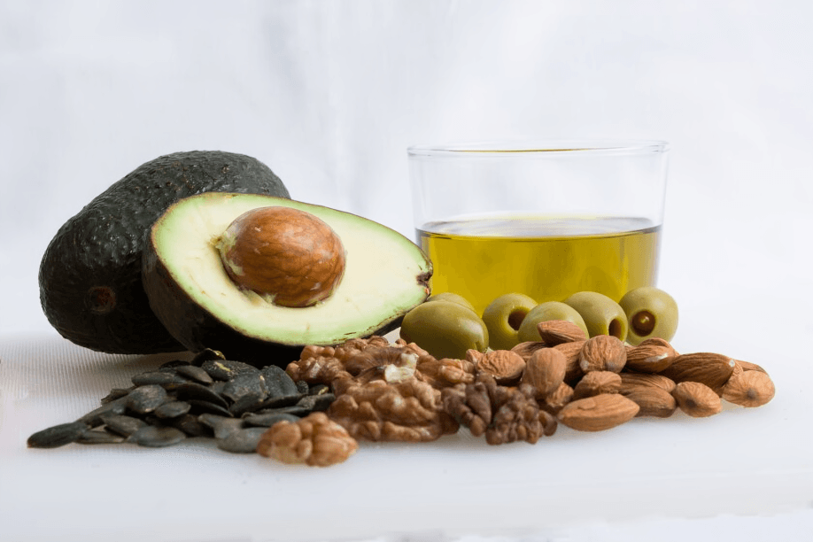 Avocado, nuts, olives, and olive oil on a white background.