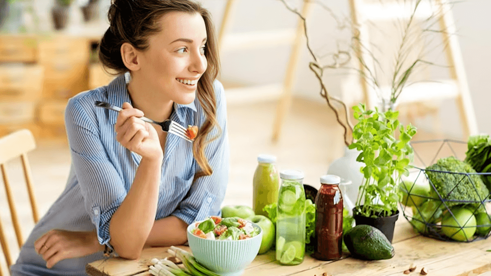 Young woman smiling and eating, surrounded by flowers.