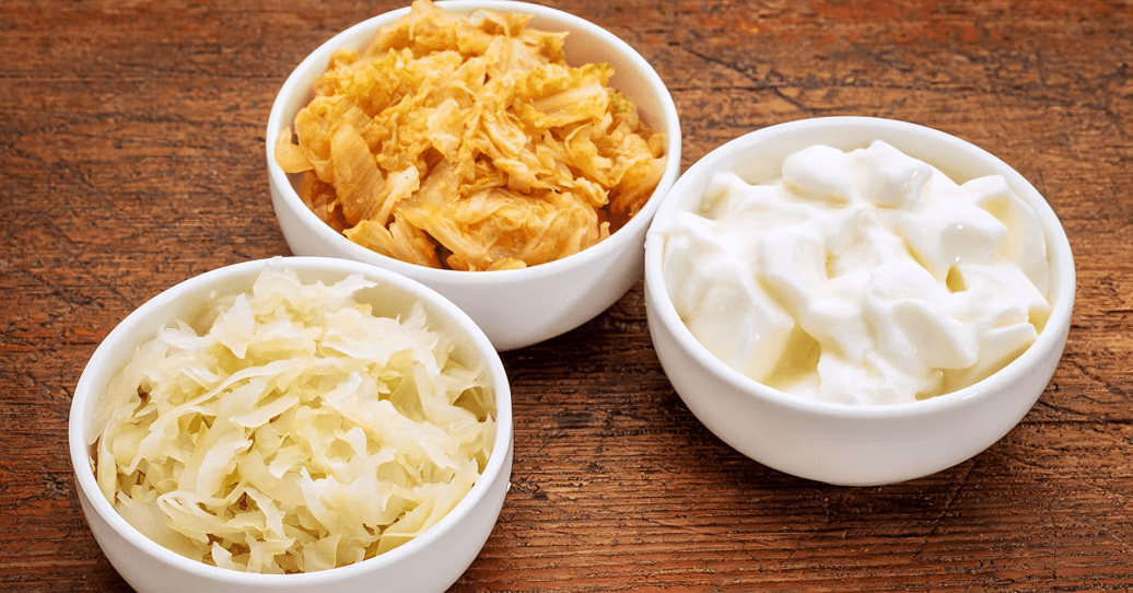 Three bowls of fermented foods on a wooden table.