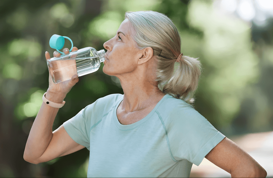 A woman drinks water from a clear bottle.