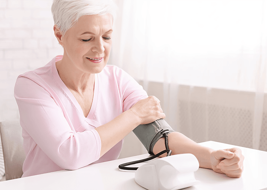 An older woman checking her blood pressure at home.