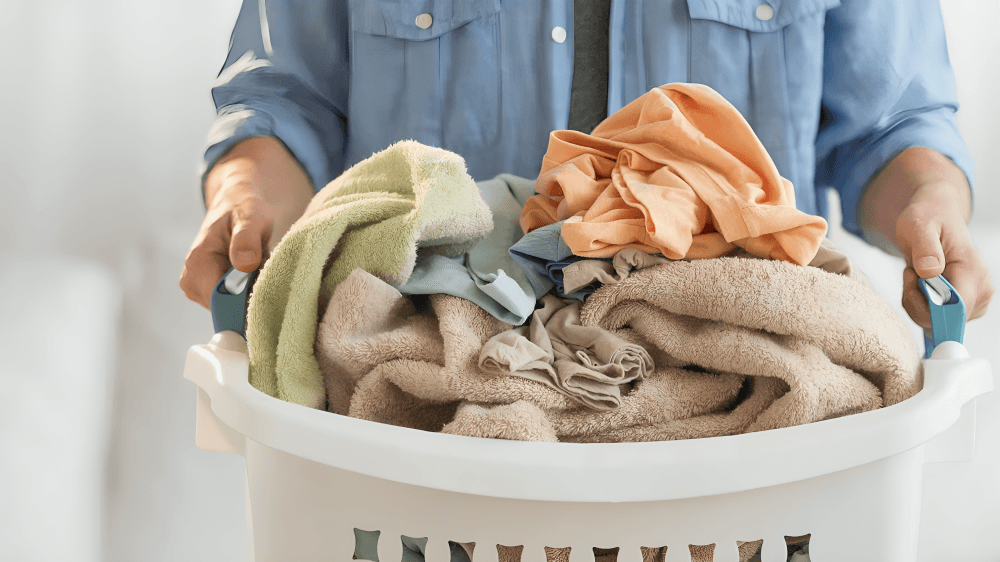 Laundry basket overflowing with various clothes and towels.
