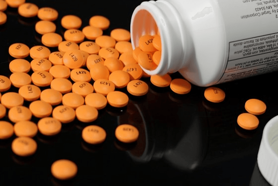 Orange pills spilled from a white bottle.