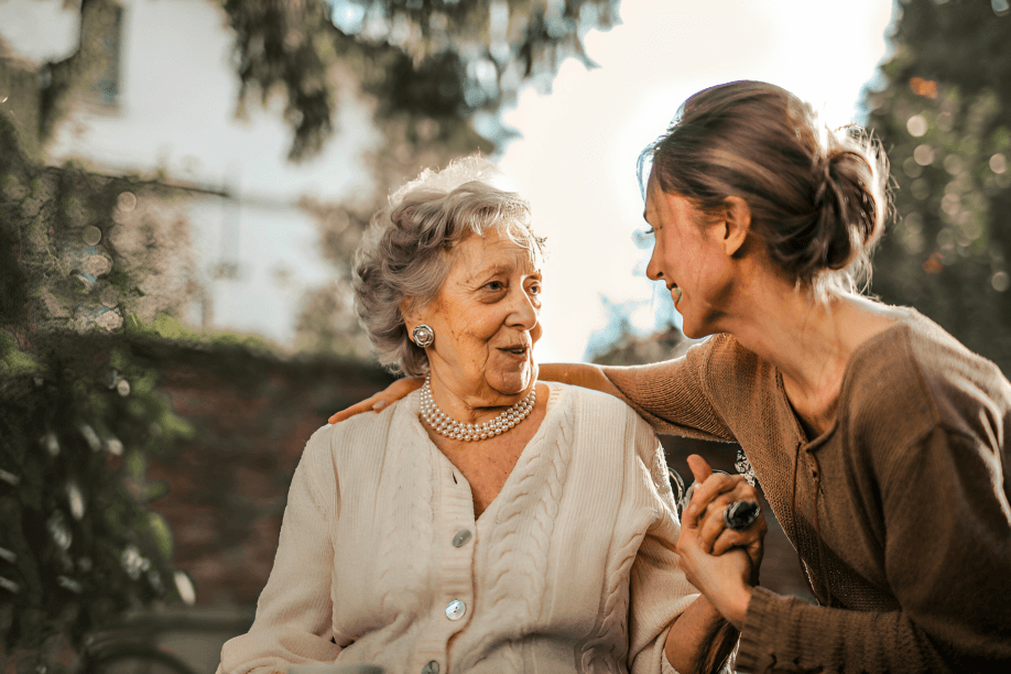 Young woman talking with elderly woman outdoors.