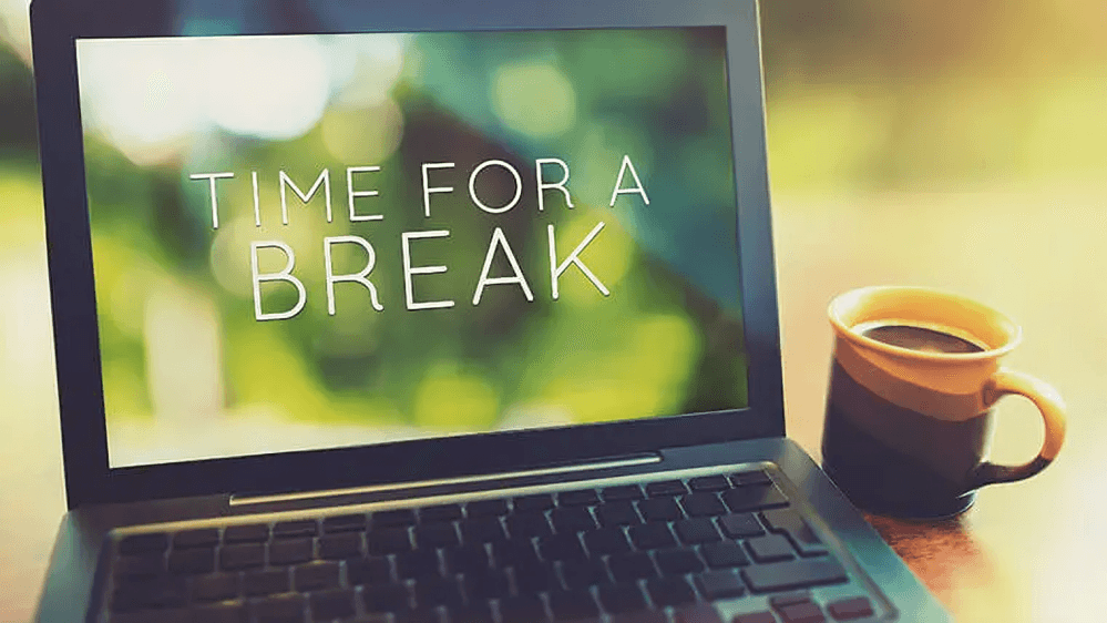 Laptop displaying "Time for a Break" with coffee mug.