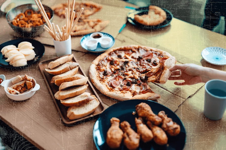 A table filled with pizza, bread, and chicken.