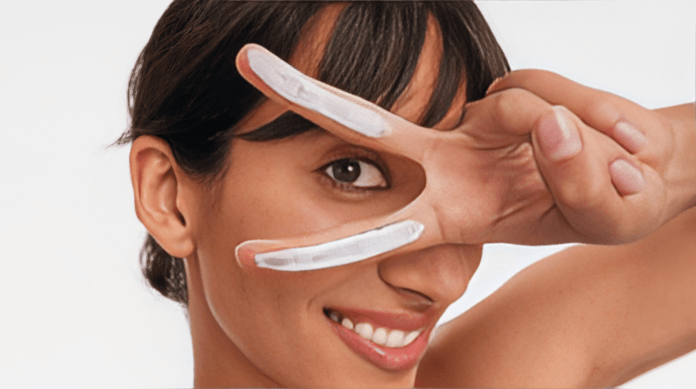 Smiling woman with white cream on her fingers.