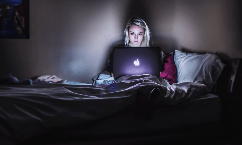 A woman in bed using laptop in a dark room