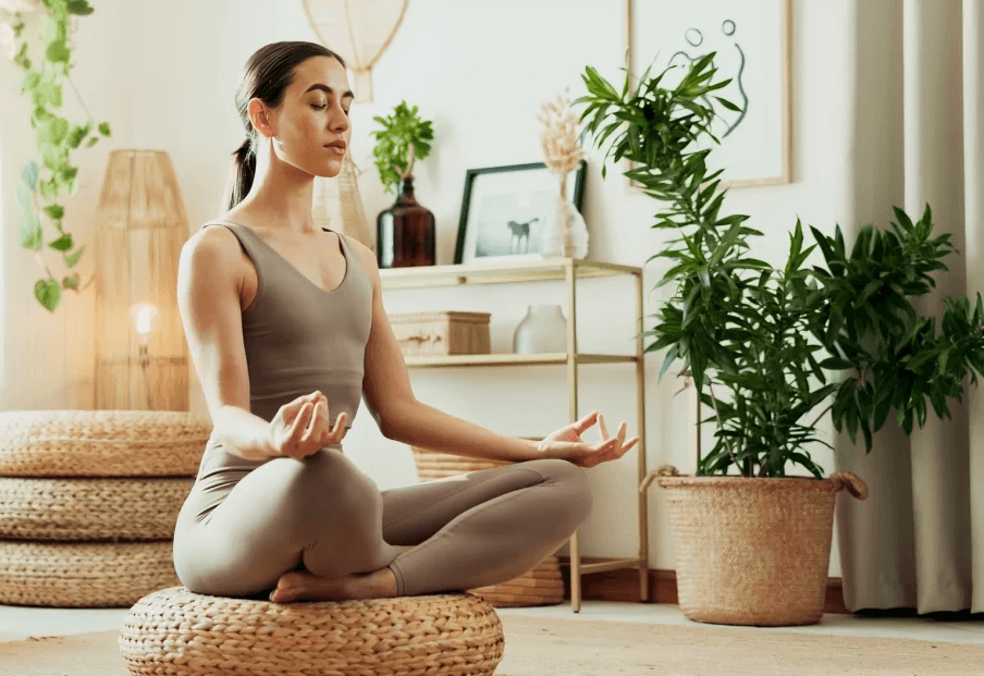 A woman meditating in lotus pose indoors.