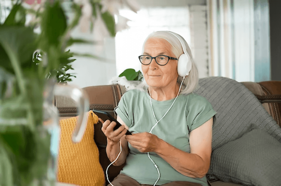 Elderly woman enjoying music with headphones and phone.