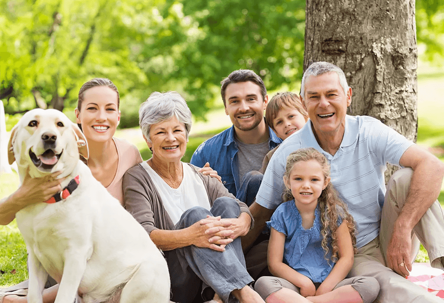 Happy multi-generational family and dog smiling outdoors.