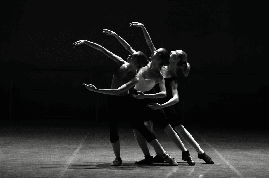 Three ballet dancers gracefully move in a synchronized performance.