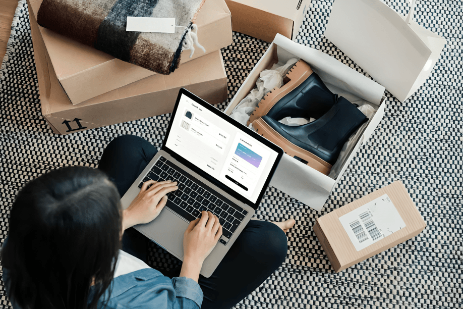 Overhead view of person on floor, laptop, and shopping boxes.