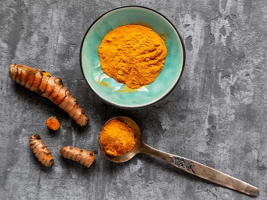 Turmeric root and powder on a gray surface.