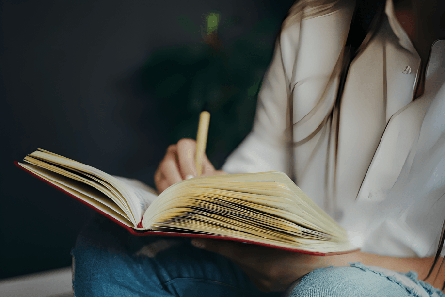 Person writing in open notebook with pen in hand.