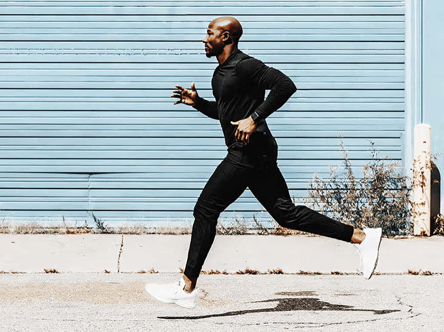 Man running outdoors in an athletic black outfit.