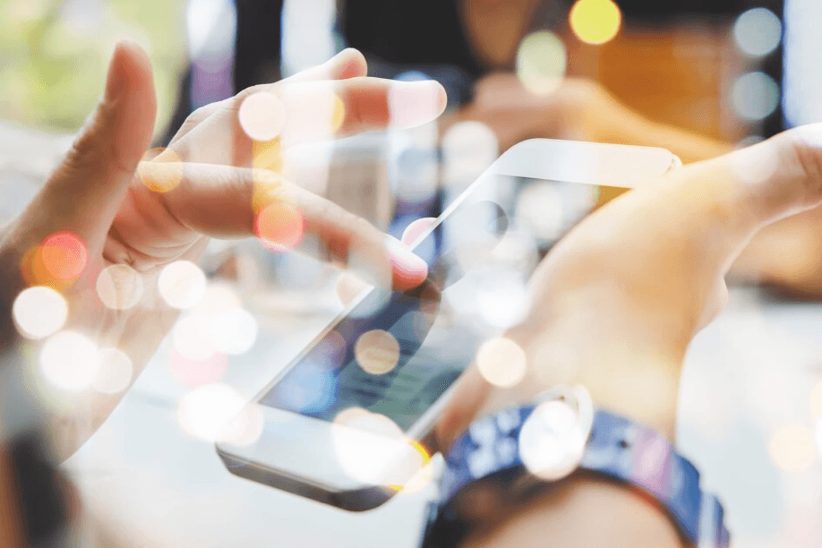 Person using smartphone with bokeh lights overlay.