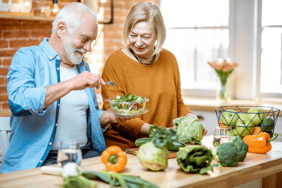 A senior couple preparing and enjoying a fresh salad.
