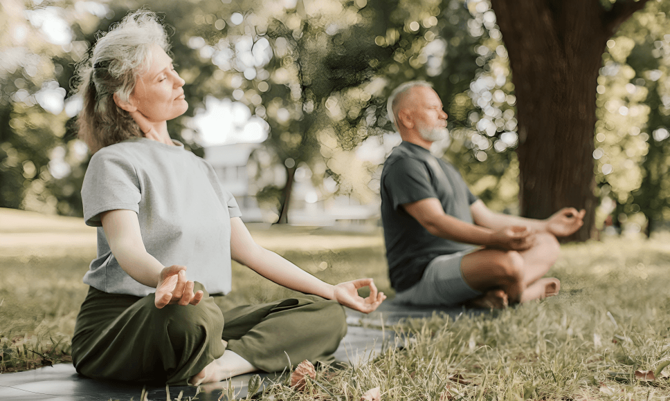 Seniors meditating outdoors, in lotus pose, peaceful.