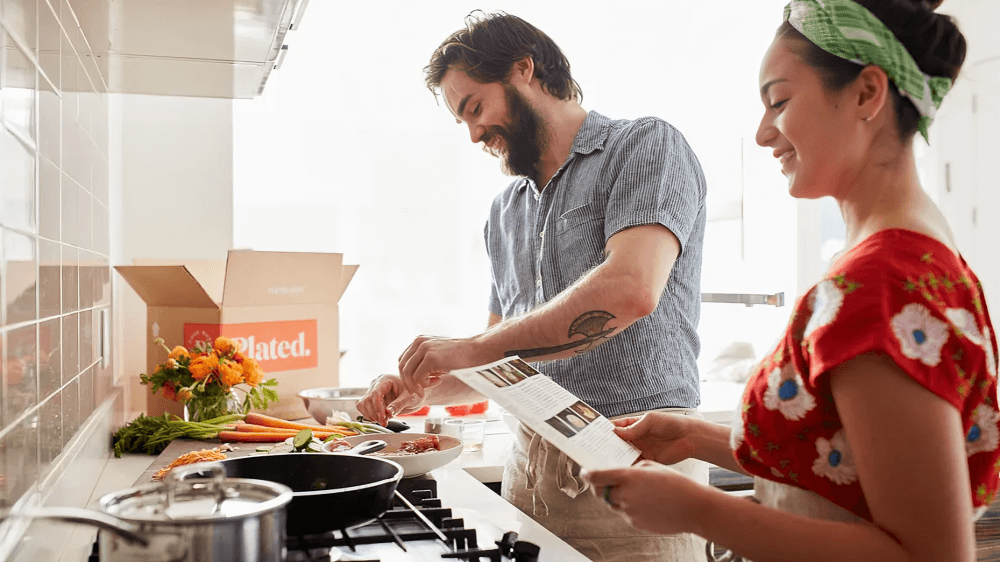 Two people cooking in a kitchen, following a recipe card.