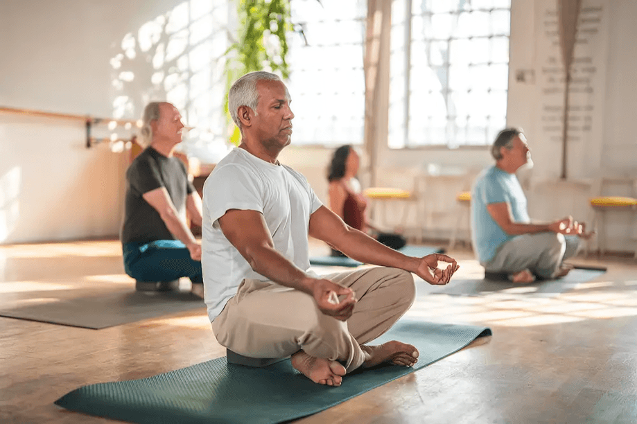 Five adults meditating on yoga mats in a studio.