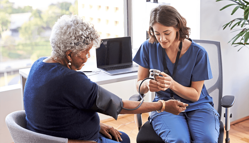 Nurse checks elderly woman's blood pressure.