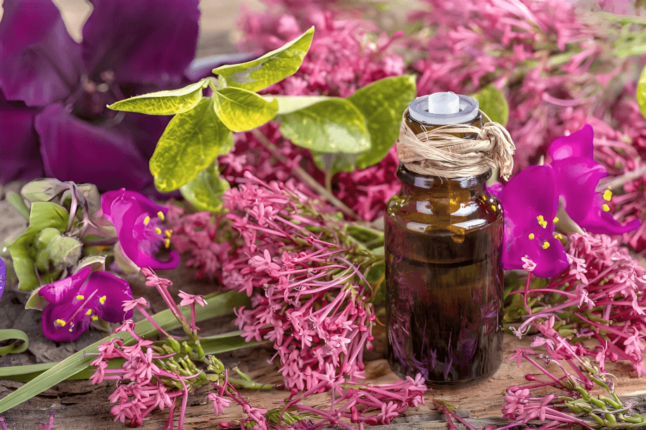 An amber bottle of essential oil amidst colorful flowers.