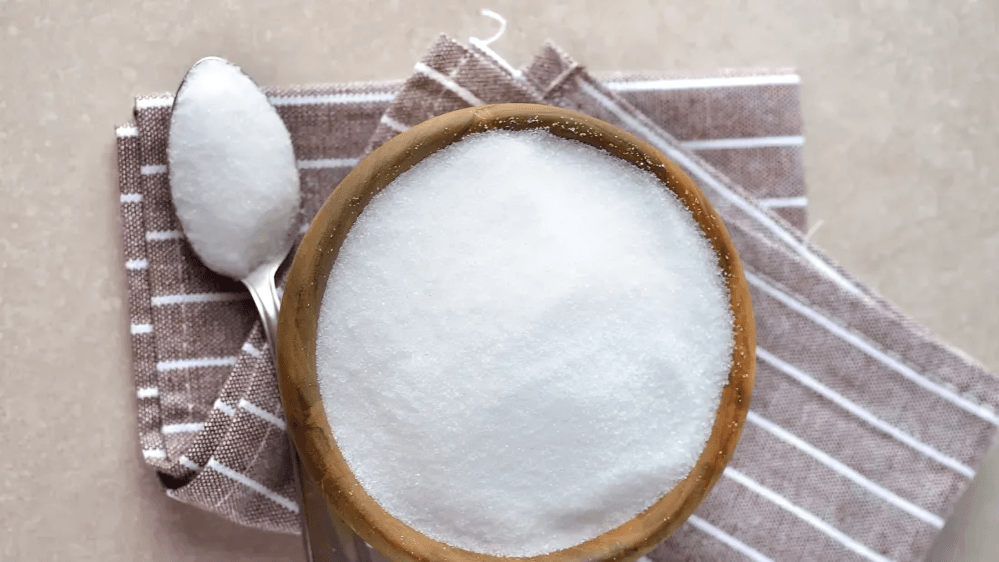 A bowl of white sugar substitute with a spoon on a towel.
