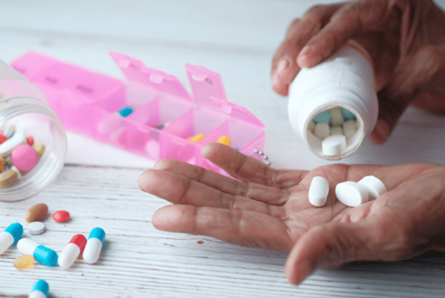 A hand splitting white tablets, on the other hand, around other tablets.