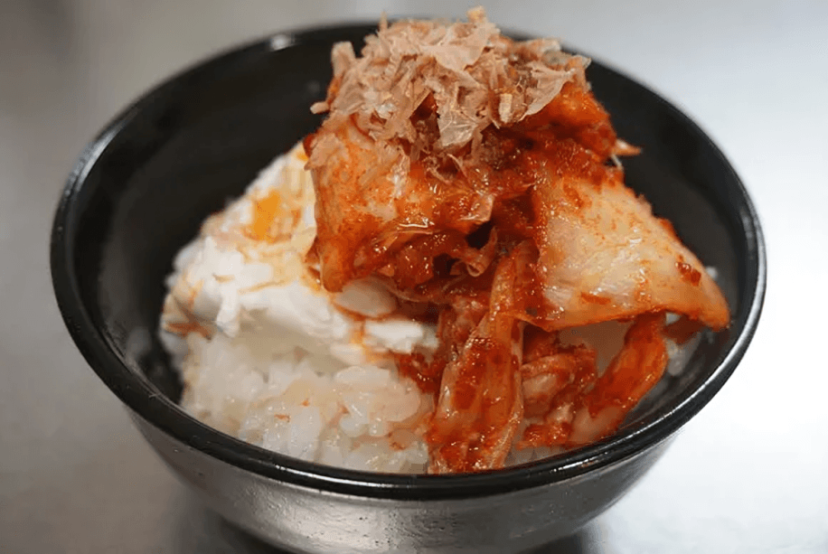 Kimchi and yogurt in a black bowl against a light background.