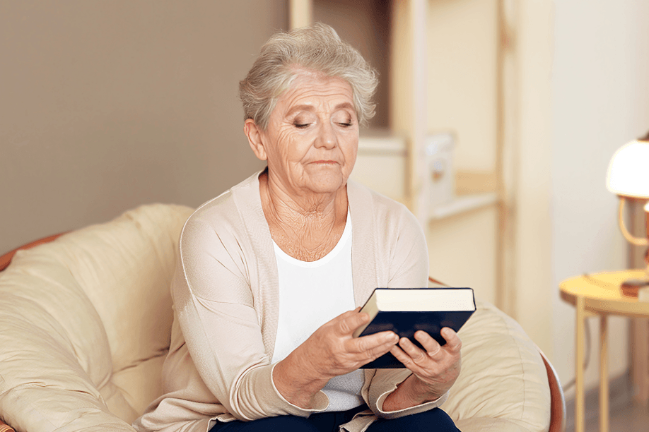 A senior woman intently reading a book indoors.