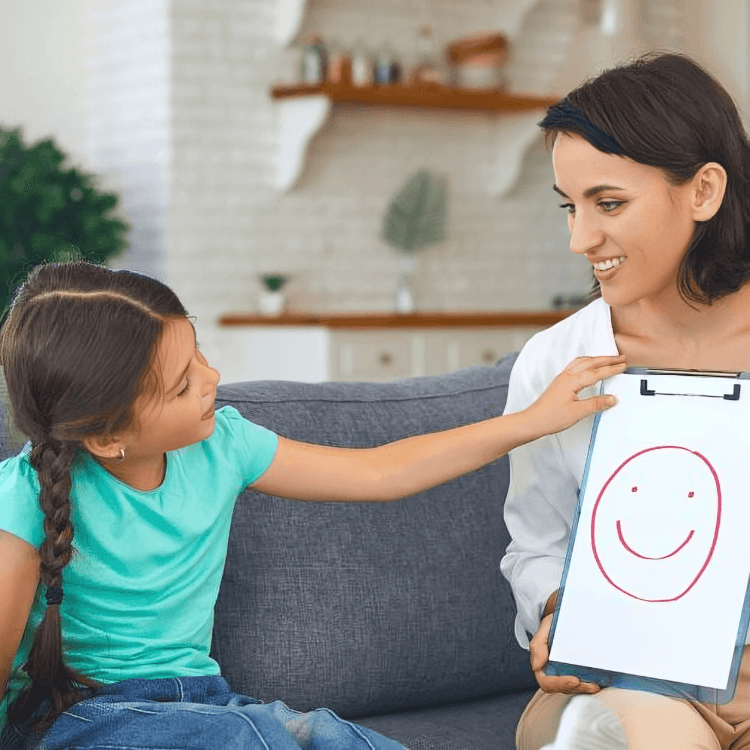 A therapist showing a happy face drawing to a child.