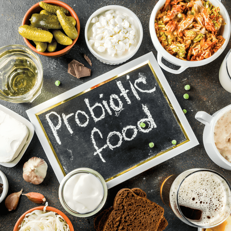 A probiotic food chalkboard surrounded by various fermented foods on a table.