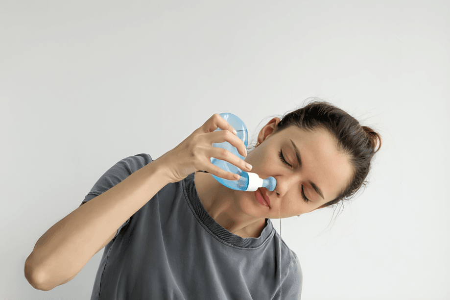 Woman irrigating her nose with a neti pot.