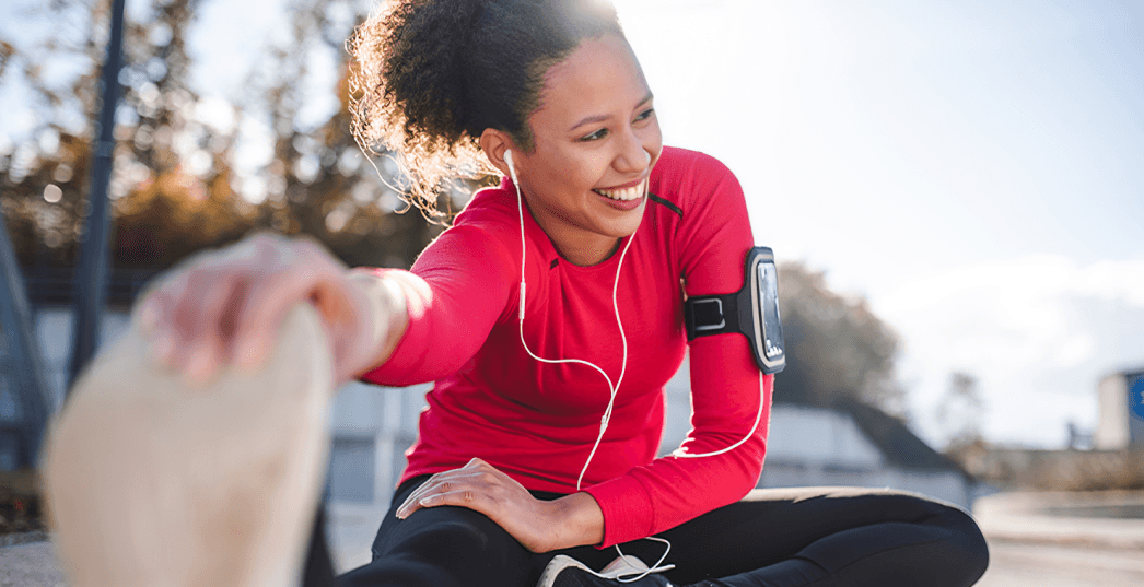 A person stretching while listening to music outdoors.