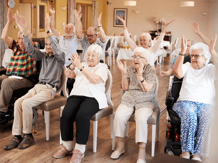Seniors happily exercising and clapping in a group.