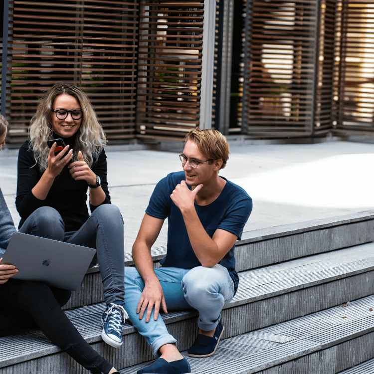 Three diverse young adults sitting on outdoor stairs.