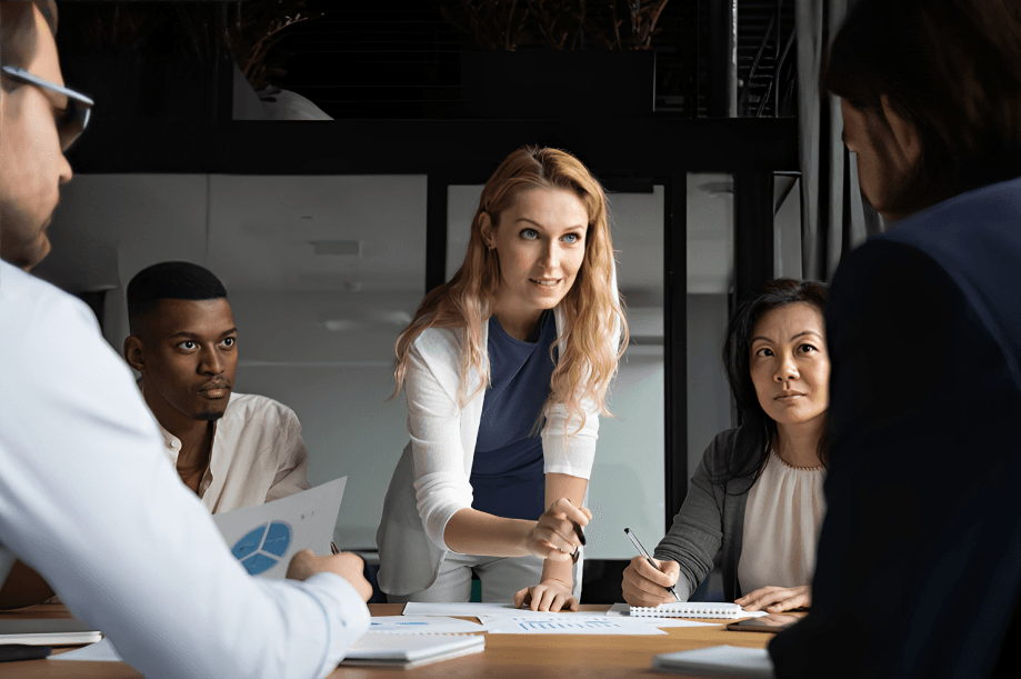 A female leader presents to diverse colleagues at a meeting.