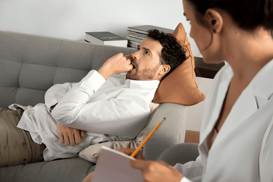 Man on couch talking to therapist taking notes.