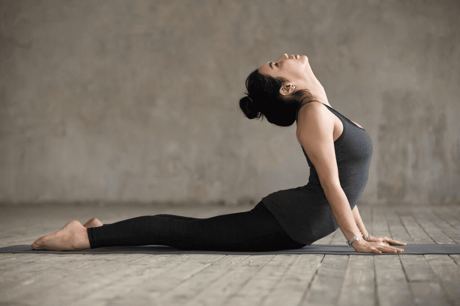 Woman in Cobra yoga pose on mat, studio background.