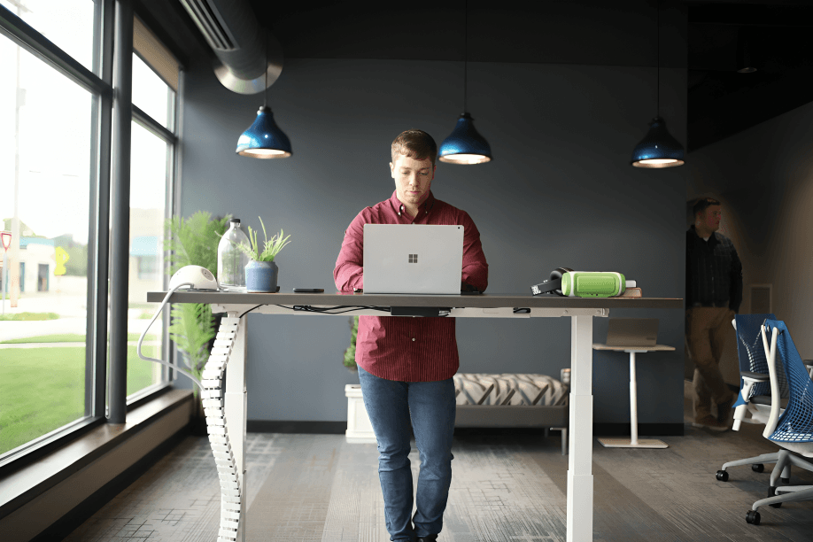 A man stands working on a laptop at a desk.