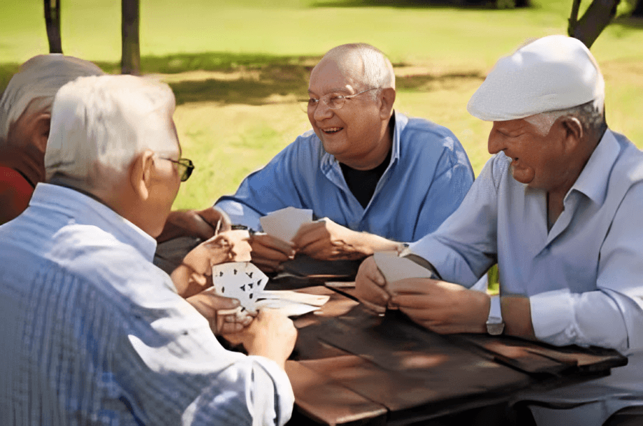 Elders happily playing cards together outdoors.