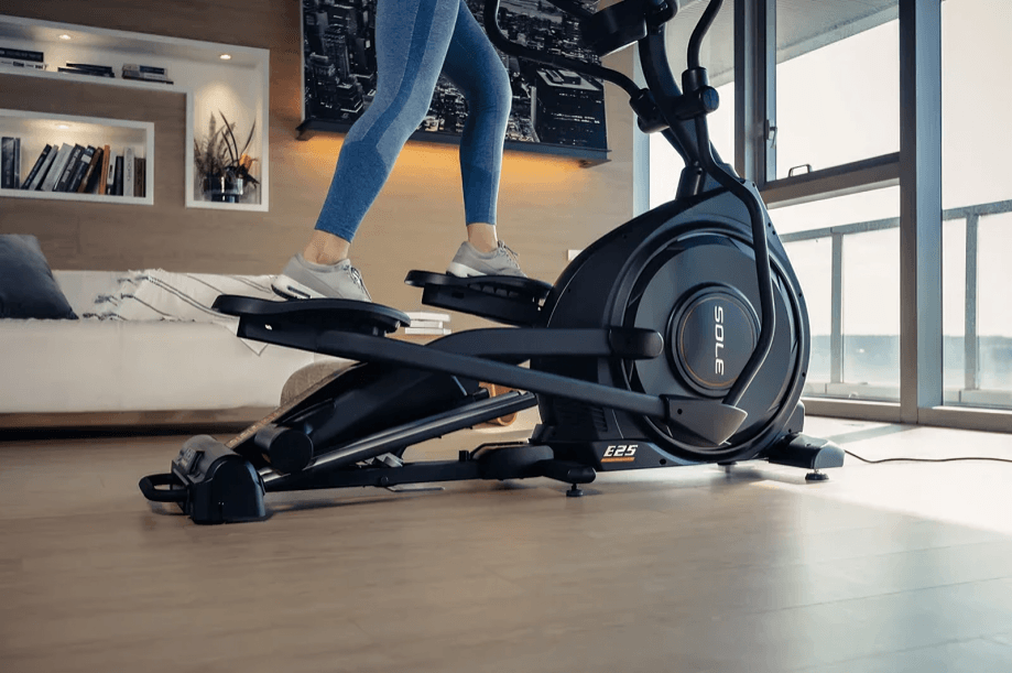 A person exercising indoors on a Sole E25 elliptical machine.
